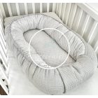 Szürke waSzürke waffle babafészek oldalnézetből – karikás díszítéssel és prémium kivitelbenffle babafészek karikás wellsoft béléssel kiságyban – biztonságos, meleg pihenőhely babáknak